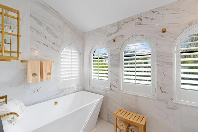 a bathroom with a bathtub windows and sink