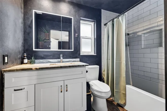 a bathroom with a granite countertop toilet sink and mirror