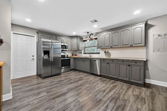 a kitchen with stainless steel appliances kitchen island granite countertop a refrigerator and a stove top oven