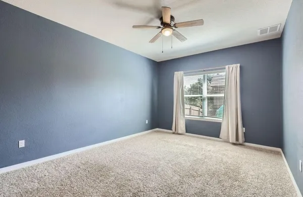 a view of a big room with windows and chandelier fan