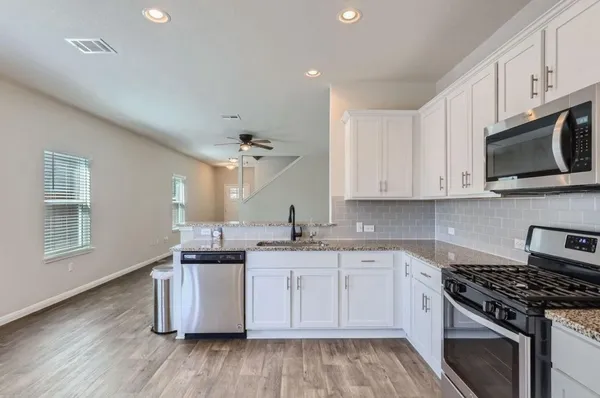 a kitchen with stainless steel appliances granite countertop a stove a sink and a microwave