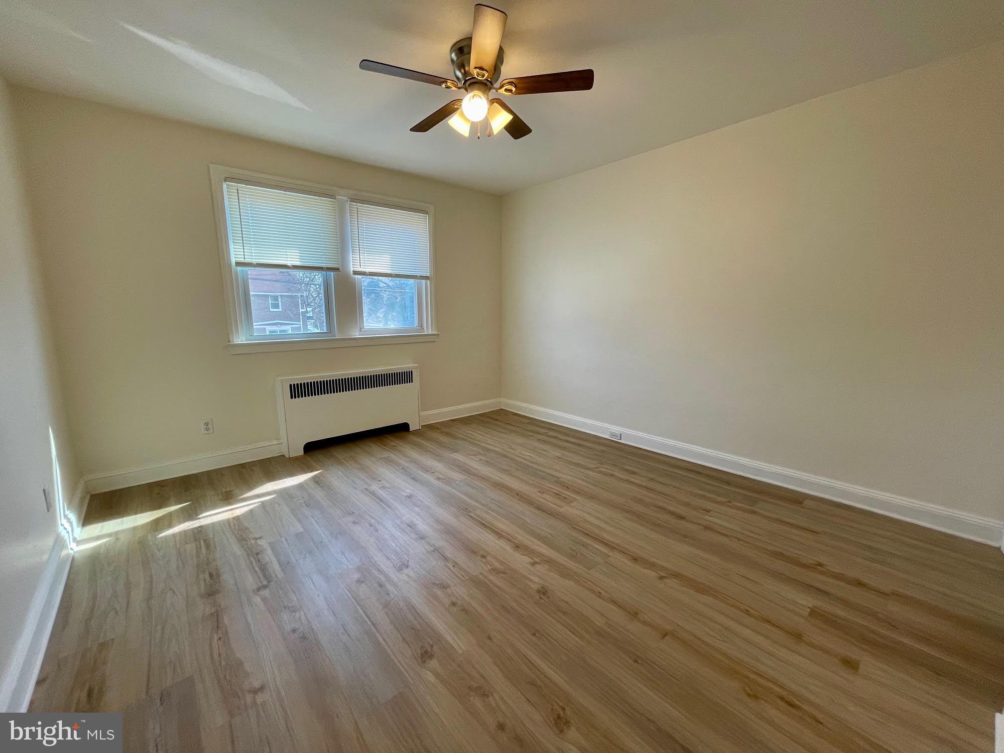 416 East Providence Road Aldan, PA 19018 - Photo 5 of 12 an empty room with wooden floor chandelier fan and windows