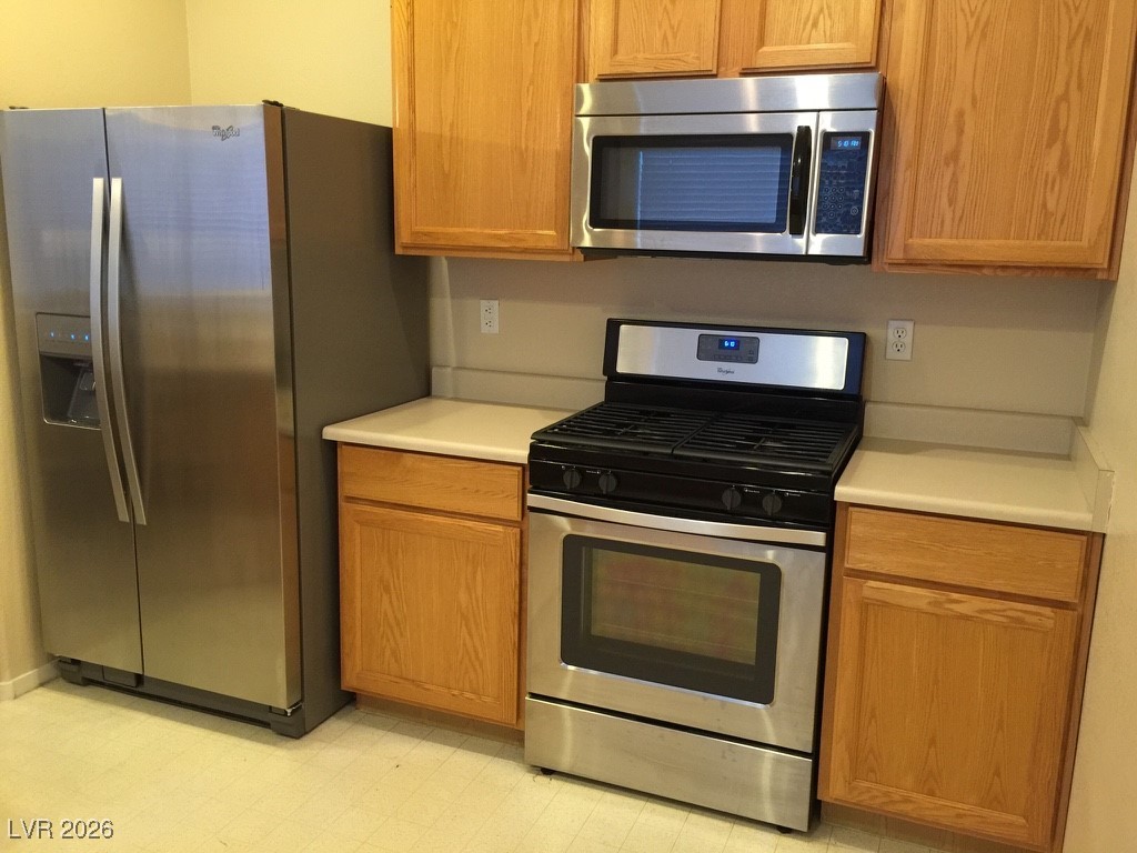 2115 Hidden Ranch Terrace Henderson, NV 89052 - Photo 20 of 30 Kitchen featuring stainless steel appliances, light countertops, light flooring, and wood finish cabinets