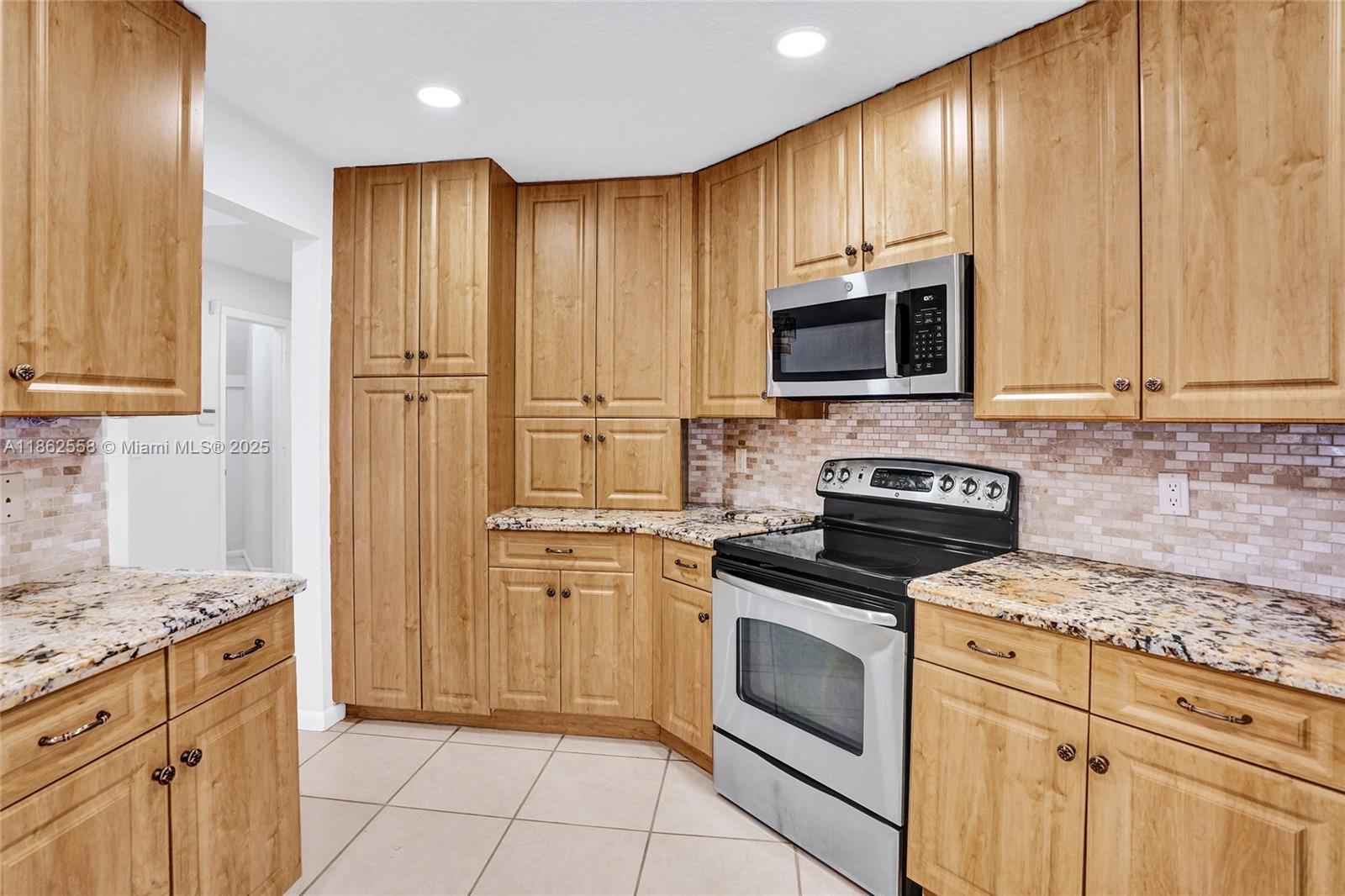 6450 Brava Way Boca Raton, FL 33433 - Photo 11 of 80 a kitchen with kitchen island granite countertop wooden cabinets and stainless steel appliances