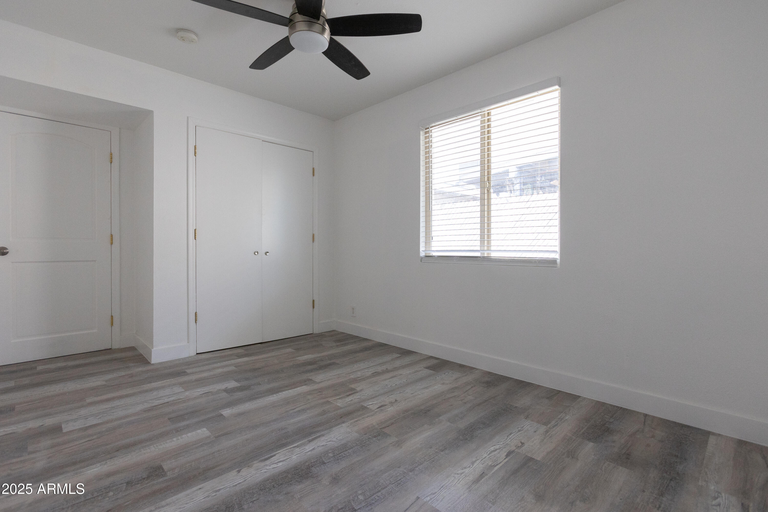 3417 East Windsor Avenue, Unit 2 Phoenix, AZ 85008 - Photo 11 of 12 an empty room with wooden floor fan and windows