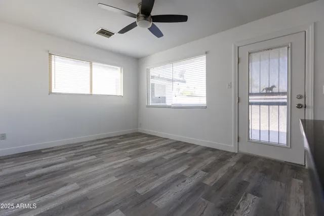 a view of empty room with wooden floor and fan