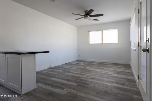 a view of a livingroom with wooden floor and a ceiling fan