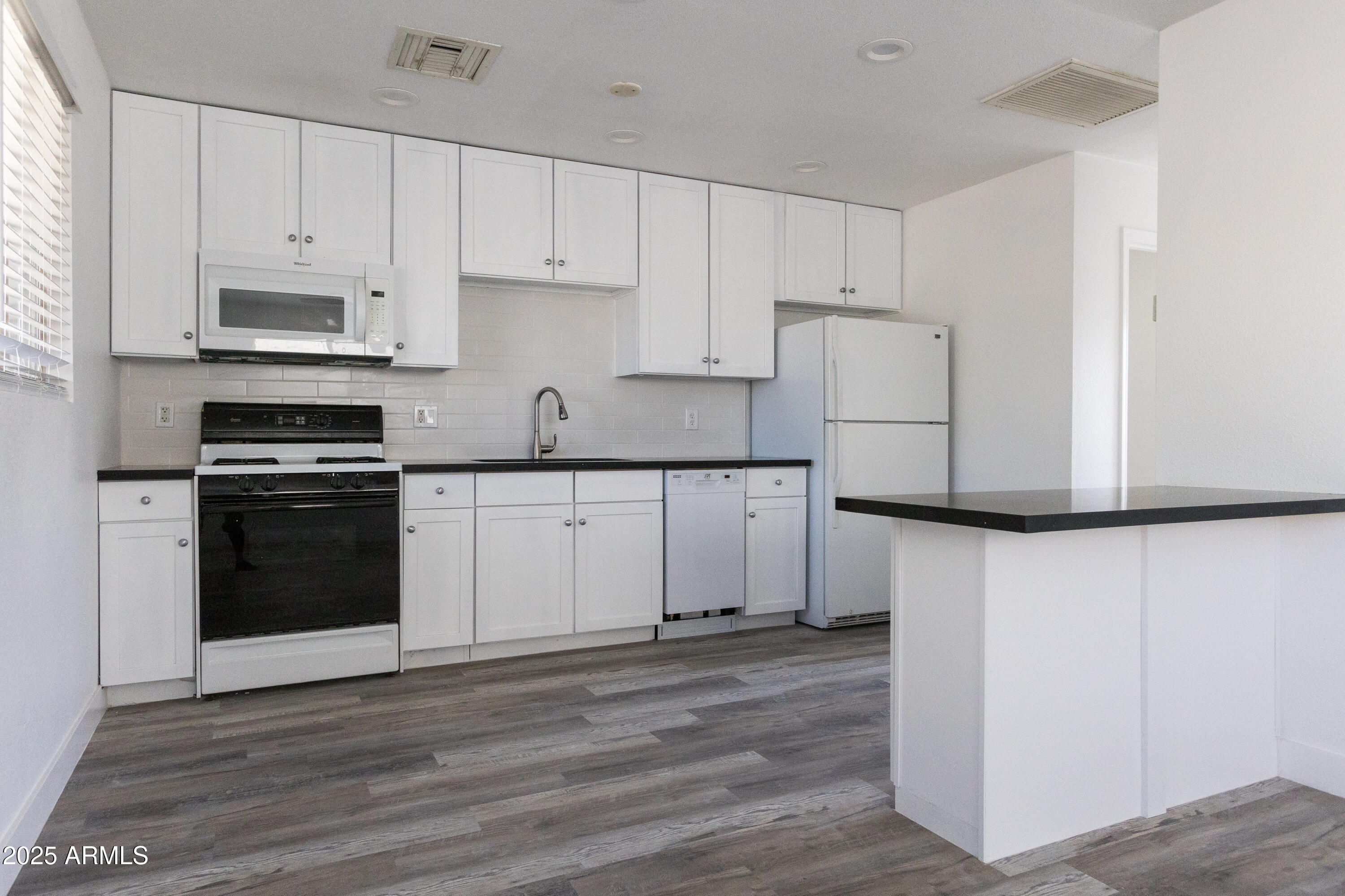 3417 East Windsor Avenue, Unit 2 Phoenix, AZ 85008 - Photo 6 of 12 a kitchen with white cabinets and stainless steel appliances