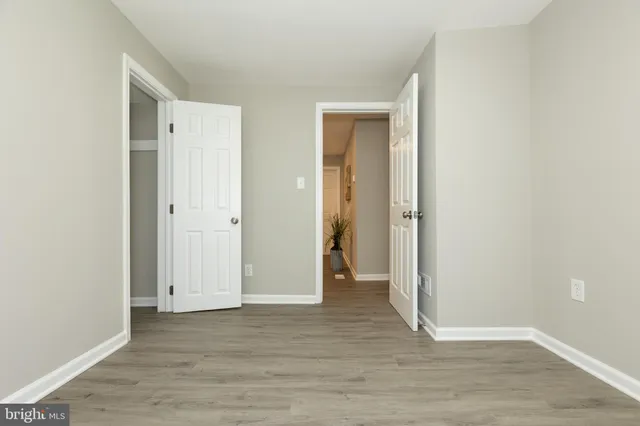 an empty room with wooden floor & closet area