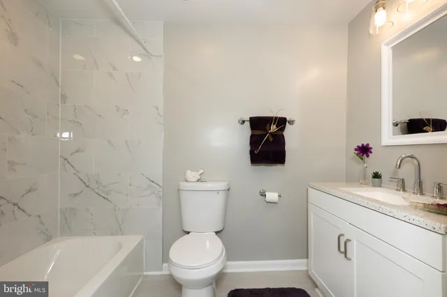 a bathroom with a granite countertop toilet sink and mirror