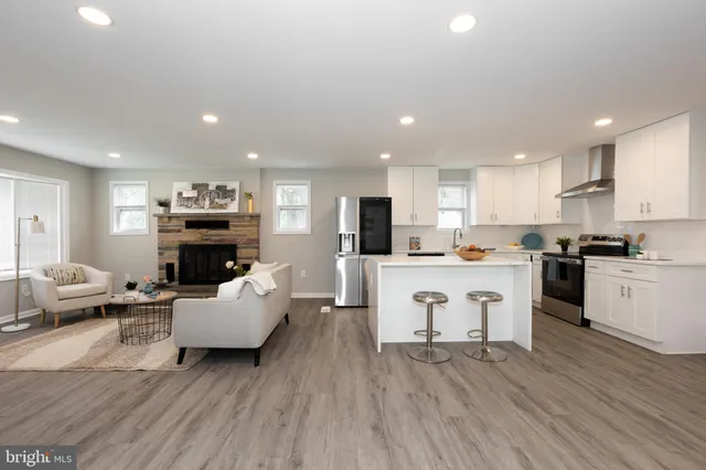 a living room with furniture a fireplace a flat screen tv and kitchen view