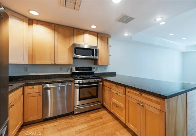 a kitchen with stainless steel appliances granite countertop a stove a sink and a microwave