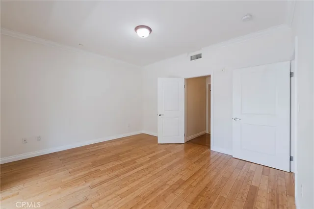 a view of an empty room with wooden floor and closet