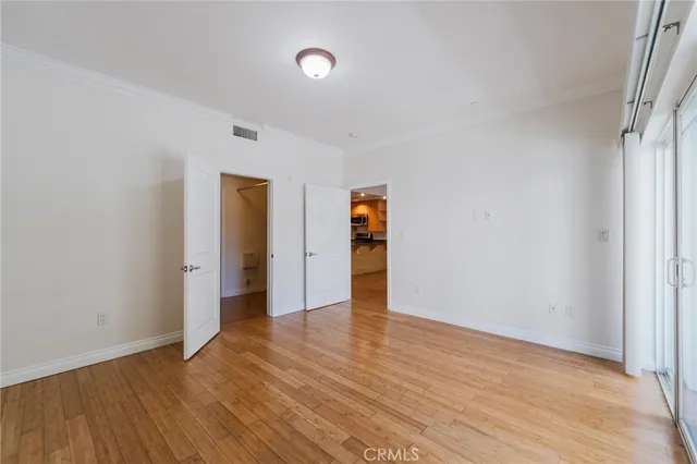 a view of an empty room with wooden floor and closet