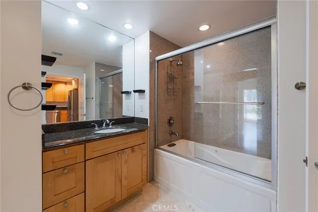 a bathroom with a granite countertop sink a mirror a bathtub and shower