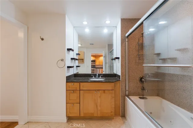 a bathroom with a granite countertop sink a mirror and a bathtub
