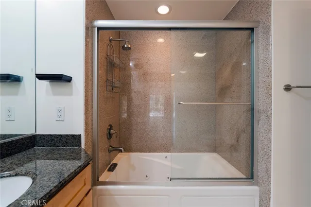 a bathroom with a granite countertop bathtub shower sink and mirror