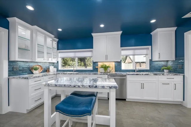 a kitchen with granite countertop white cabinets and white appliances