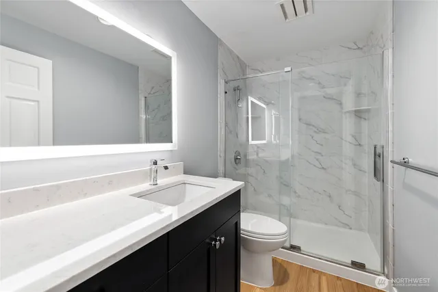 a bathroom with a granite countertop sink toilet a mirror and shower