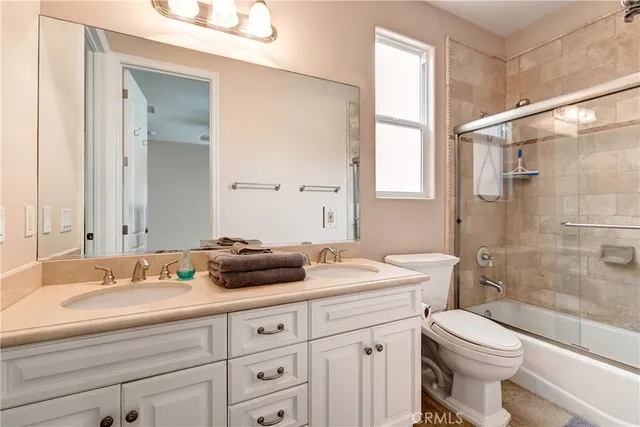 a bathroom with a double vanity sink toilet mirror and shower