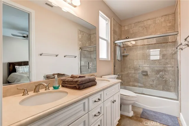a bathroom with a granite countertop sink a toilet a mirror and shower