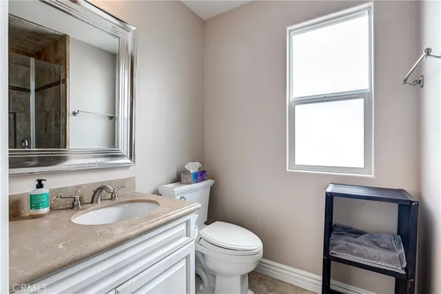 a bathroom with a granite countertop sink toilet and mirror
