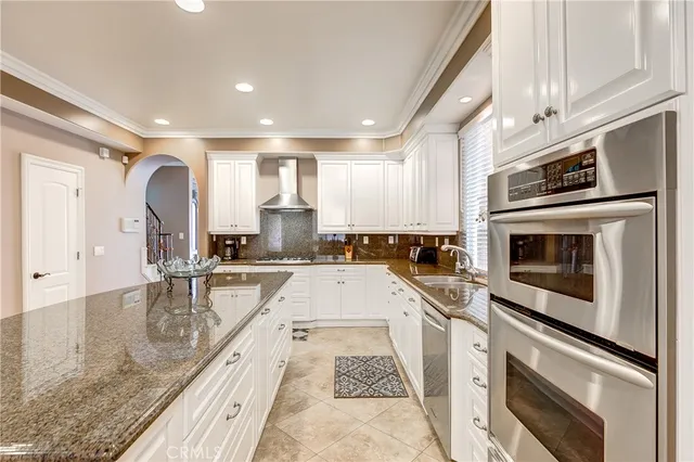 a large kitchen with granite countertop a stove top oven a sink a counter space and cabinets
