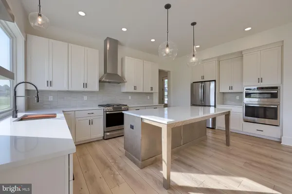 a kitchen with a sink stainless steel appliances and wooden floor
