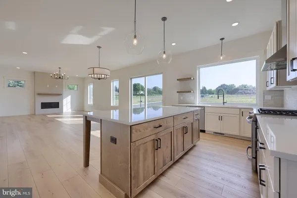 a large kitchen with a large counter top a sink stainless steel appliances and cabinets