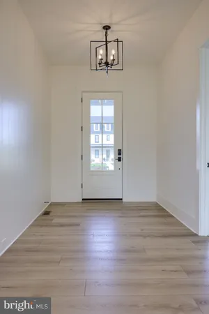 an empty room with wooden floor chandelier and windows