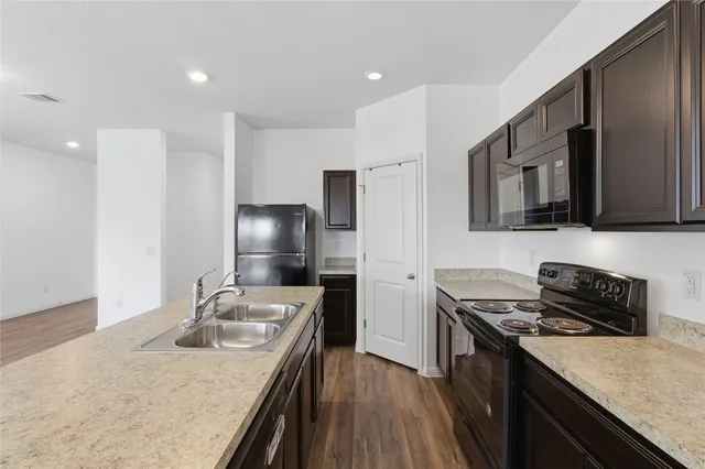 a view of a kitchen with stainless steel appliances granite countertop a refrigerator and a sink