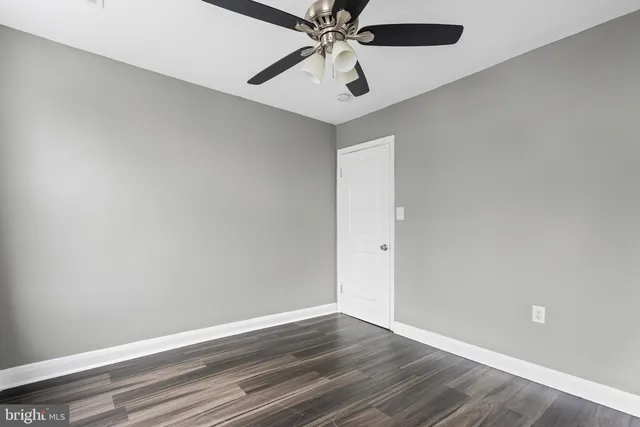 an empty room with wooden floor closet and windows