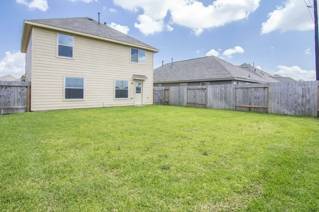 a view of a house with a yard and a large tree