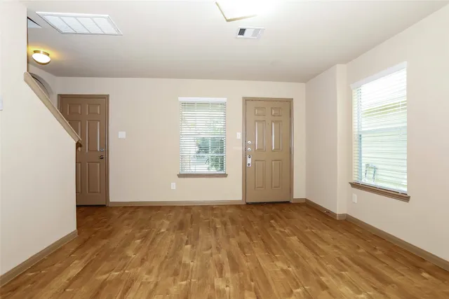 a view of an empty room with wooden floor and a window
