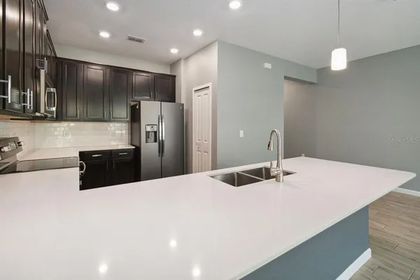 a large white kitchen with a sink and refrigerator