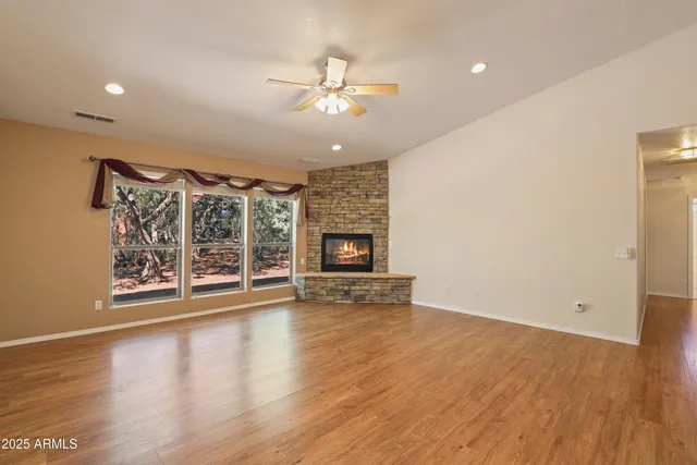 a view of an empty room with wooden floor fireplace and a window