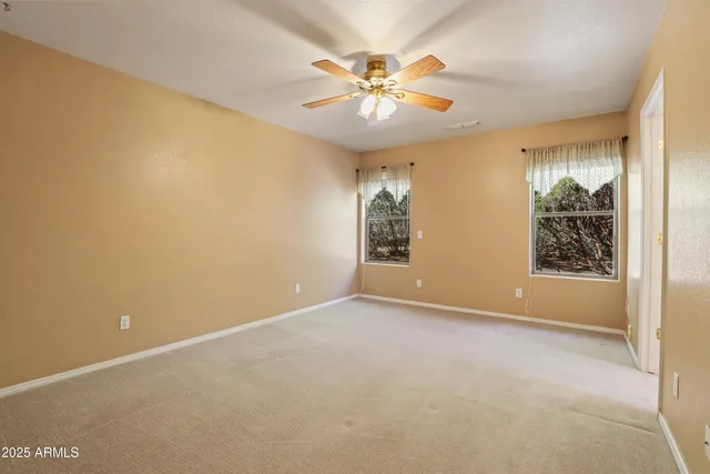 an empty room with window and chandelier fan