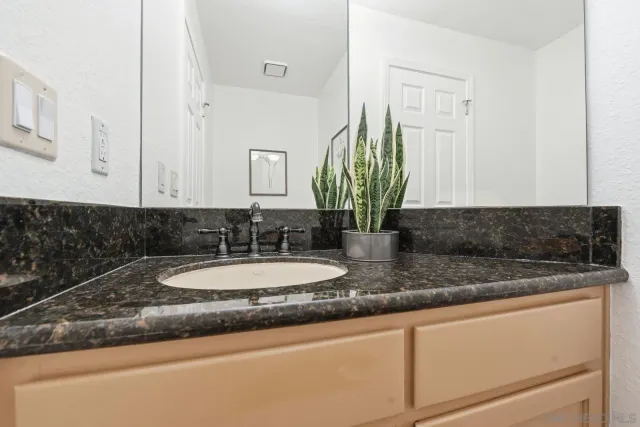 a bathroom with a granite countertop sink and a mirror