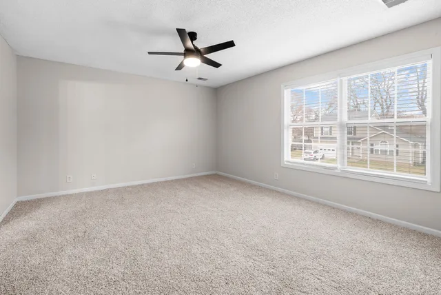 an empty room with windows and fan