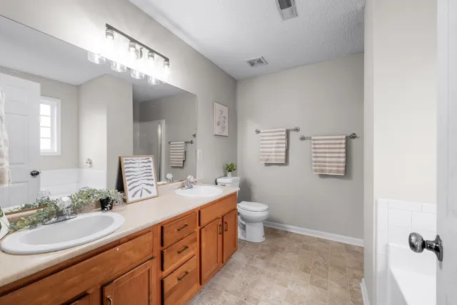 a spacious bathroom with a double vanity sink a mirror and a toilet