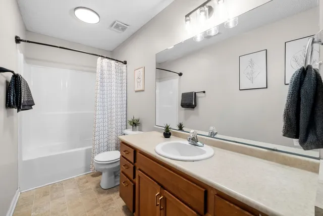 a bathroom with a sink a toilet a mirror and shower