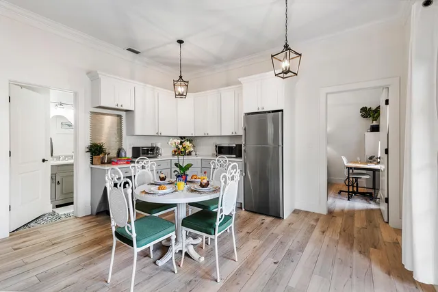 a dining room with stainless steel appliances granite countertop a dining table chairs refrigerator and cabinets