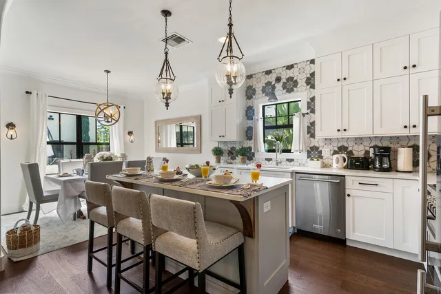 a kitchen with stainless steel appliances kitchen island granite countertop a sink a stove a dining table and chairs