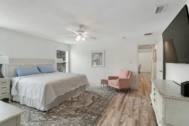 a spacious bedroom with a bed and wooden floor