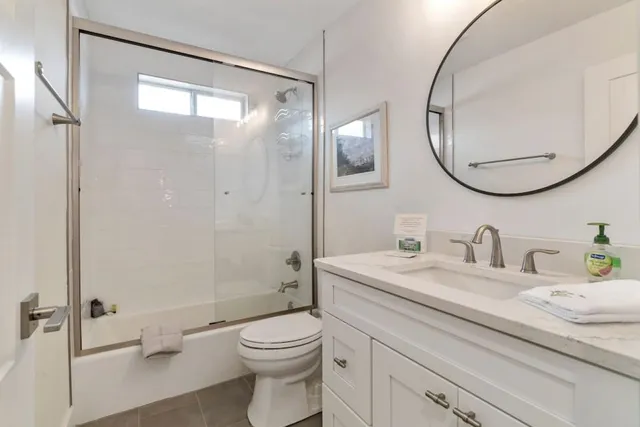 a bathroom with a granite countertop sink toilet mirror vanity and shower