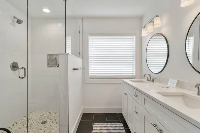 a bathroom with a double vanity sink mirror and shower