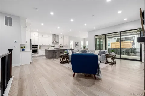 a living room with stainless steel appliances granite countertop furniture wooden floor and a view of kitchen