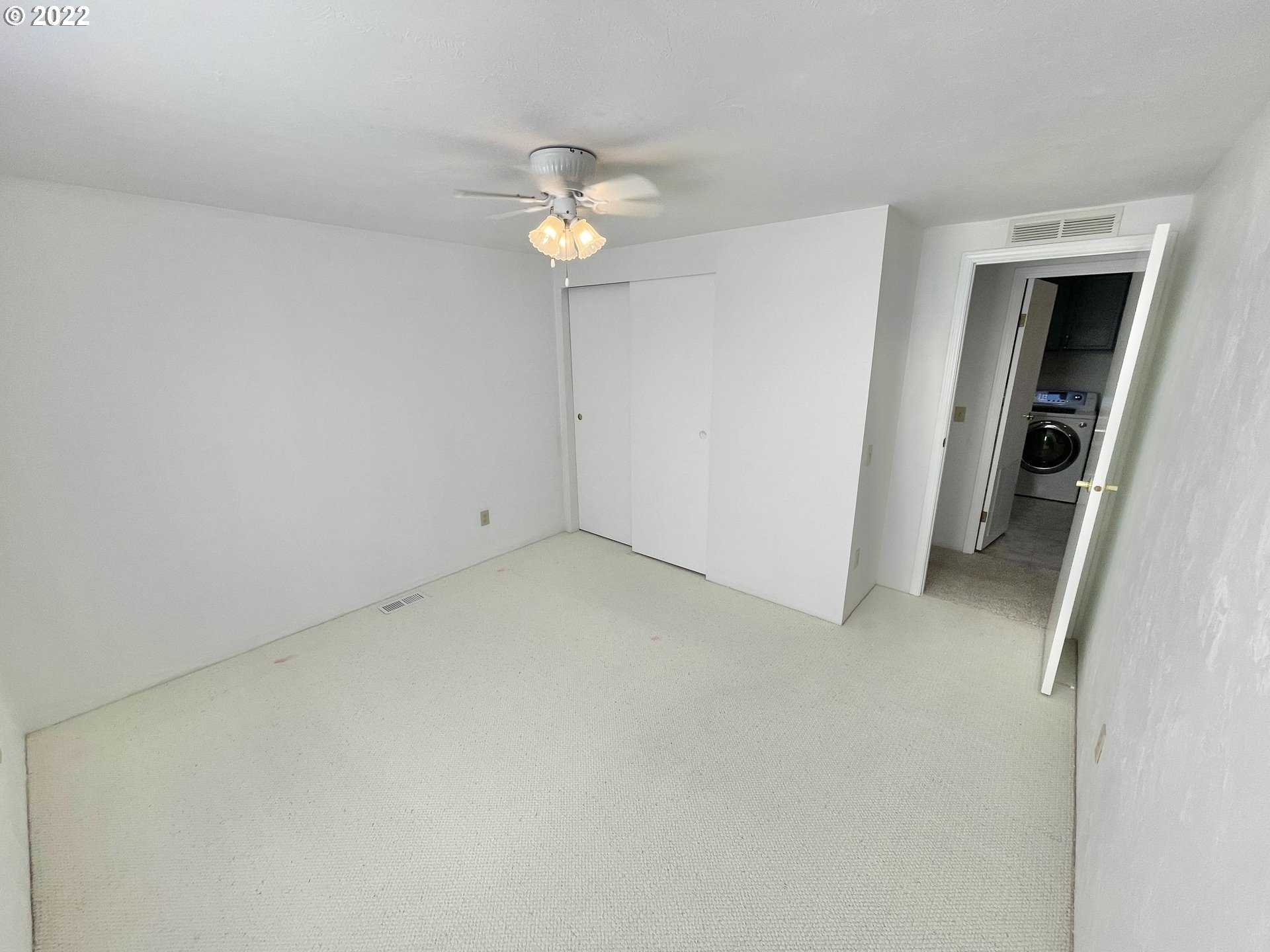 100 River Bend Road, Unit 101 Reedsport, OR 97467 - Photo 12 of 30 an empty room with a chandelier fan and wooden floor