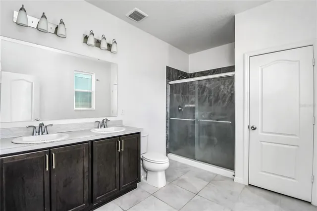 a bathroom with a double vanity sink toilet and mirror