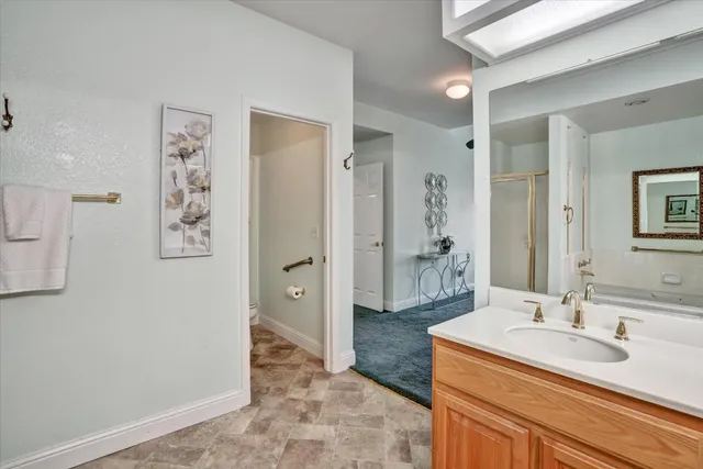 a bathroom with a granite countertop sink a mirror and a shower